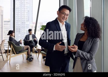 Portrait d'un manager masculin souriant debout à côté d'une collègue féminine au bureau Banque D'Images