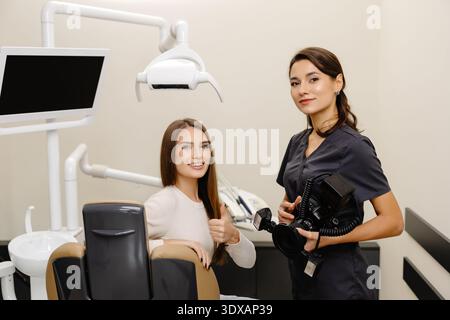 Femme dentiste photographiant avec un appareil photo professionnel le résultat de son travail en clinique. Banque D'Images