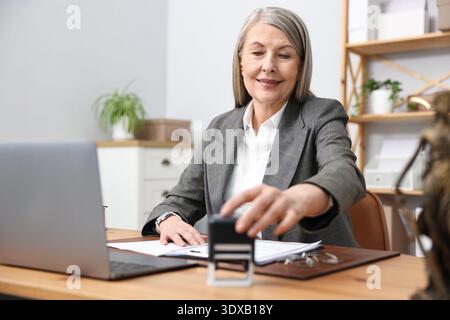 Notaire prenant timbre au bureau en bois dans le bureau Banque D'Images