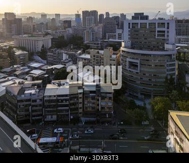 Vue aérienne de bâtiments projetant de longues ombres dans la lumière dorée, juxtaposés contre les montagnes lointaines, Taipei, Taipei City, Taiwan. Banque D'Images