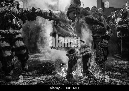 Le 17 février 2026, Un personnage masqué dans un masque de diable en bois sculpté à la main saute sur des braises pendant le carnaval médiéval d'Entrudo à Vila Boa de Ousilhao Banque D'Images