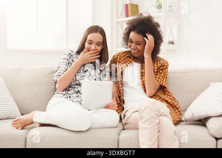 Deux amis profitent du temps ensemble tout en regardant un appareil dans un espace intérieur confortable avec lumière naturelle Banque D'Images