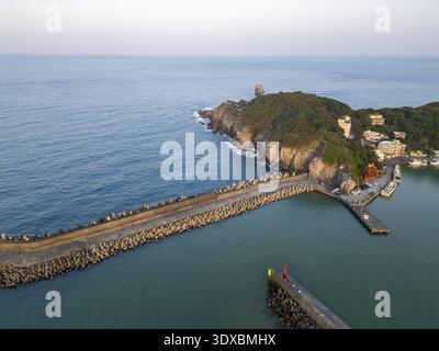 Vue aérienne d'un littoral spectaculaire où la mer turquoise calme rencontre un promontoire rocheux accidenté surmonté d'une végétation luxuriante, Keelung, Keelung City, Taiwa Banque D'Images