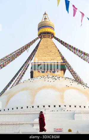 Un moine bouddhiste marchant sur la terrasse du dôme blanc du Boudhanath Stupa à Katmandou, au Népal. Banque D'Images