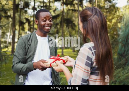 Personnes donnant des cadeaux dans un parc pendant l'après-midi Banque D'Images