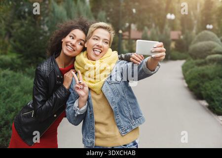 Deux amis se font des visages stupides en prenant un Selfie dans un parc pendant l'automne Banque D'Images
