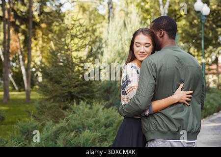 Couple profite d'un moment ensemble dans un parc entouré d'arbres verts et de plantes pendant la journée Banque D'Images