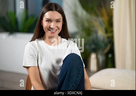 Jolie jeune femme souriante à la maison se sentant à l'aise Banque D'Images