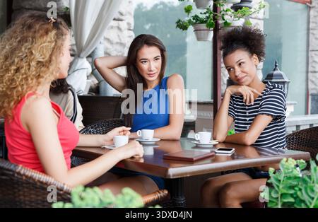 Les amis apprécient les boissons et la conversation dans un café pendant un après-midi ensoleillé en été Banque D'Images