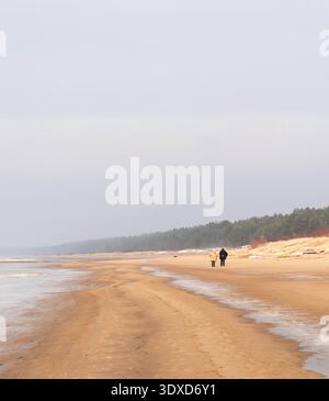 Les gens marchent le long d'une large plage de sable de la mer Baltique à Lilaste, Lettonie Banque D'Images