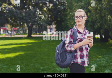 Un jeune adulte se tient dans un parc avec de l'herbe verte Banque D'Images