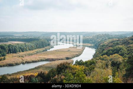 Vue aérienne de la rivière sinueuse dans la vallée d'automne. Vue en angle élevé sur la rivière Ros serpentant à travers une vallée remplie de feuillage d'automne et de roseaux dorés. Banque D'Images