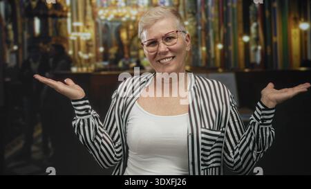 Femme haussant les paumes vers le haut et les mains ouvertes à l'intérieur de l'église, souriant et inclinant la tête devant l'autel ; acceptation allégée. Banque D'Images