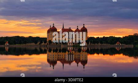 Grand plan du château de Moritzburg au coucher du soleil, avec son architecture baroque parfaitement reflétée dans les eaux calmes de l'étang du château en Saxe, en Allemagne. Banque D'Images