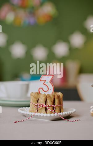 Gâteau d'anniversaire vertical de chien avec bougie numéro trois célébrant l'anniversaire d'animal de compagnie Banque D'Images