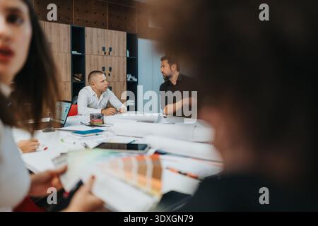 L'équipe professionnelle discute des idées lors d'une réunion de bureau moderne autour d'une table blanche Banque D'Images