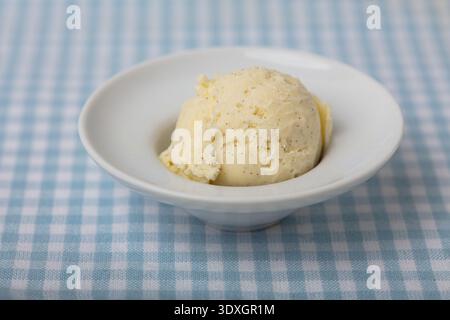 Gros plan haute résolution d'une seule boule de crème glacée crémeuse à la vanille servie dans un petit bol en porcelaine blanche Banque D'Images