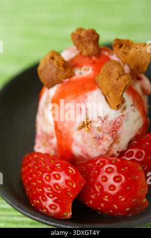 Gros plan d'une boule de glace artisanale au fromage à la fraise agrémentée d'un filet de sirop de fruits rouges éclatant Banque D'Images