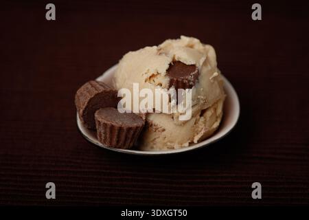 Gros plan d'une seule boule de crème glacée crémeuse au beurre d'arachide avec des morceaux de bonbons au chocolat et au beurre de noix visibles Banque D'Images