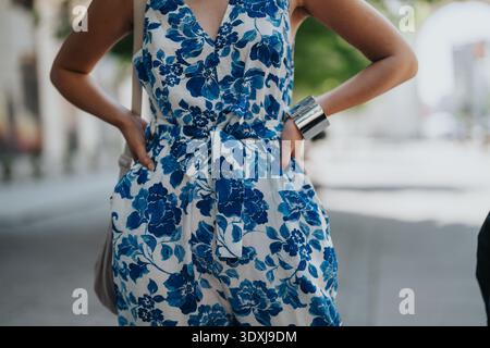 Femme en combinaison bleue florale se tient en toute confiance à l'extérieur avec les mains sur les hanches Banque D'Images