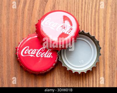 Erevan, Arménie - 18 janvier 2026 : quelques bouchons en étain rouge de la bouteille de Coca-Cola se referment sur fond de table en bois Banque D'Images