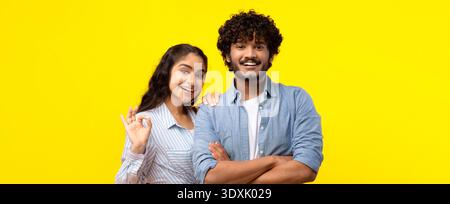 Deux amis souriant sur un fond jaune vif tout en posant pour la caméra Banque D'Images