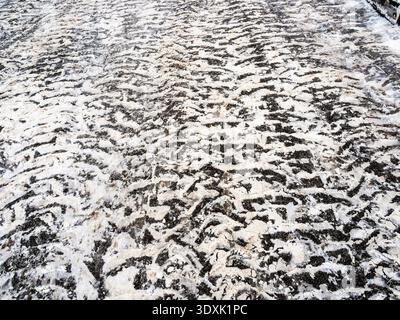 surface de la route asphaltée avec des marques de neige des pneus de voiture en ville sur la journée nuageuse d'hiver Banque D'Images