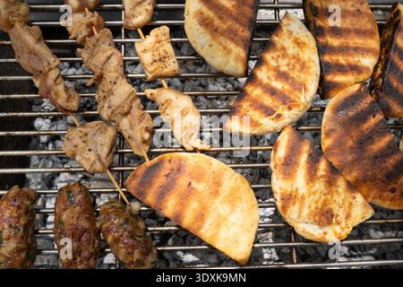 Arayes, kebabs et brochettes de poulet grésillant à feu vif sur un barbecue. Banque D'Images