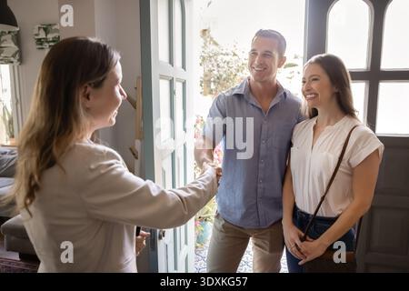 Agent immobilier poignée de main avec couple, salutation, debout dans l'entrée de la maison Banque D'Images