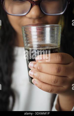 Enfant tenant un verre de boisson noire en vue rapprochée Banque D'Images