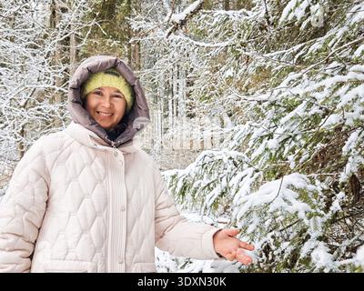 Les femmes profitent d'une journée d'hiver dans un parc forestier enneigé tout en riant et en marchant sur un pont ensemble dans la nature Banque D'Images
