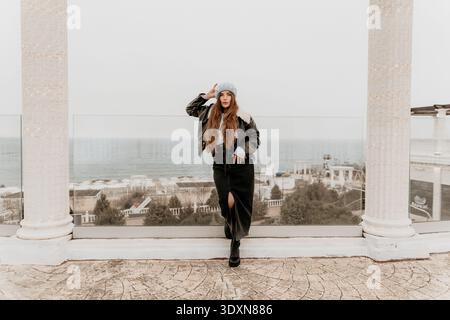 Femme portrait de mode fille élégante en veste en cuir et béret posant sur la terrasse à Sébastopol Crimée surplombant la mer Banque D'Images