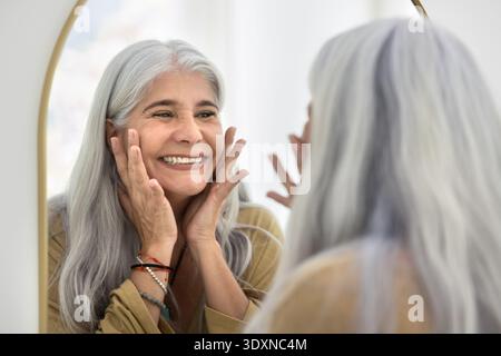 Heureuse femme Latina toucher sa peau fraîche après la procédure de cosmologie Banque D'Images