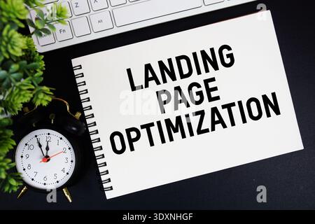 Landing page texte d'optimisation écrit sur le bloc-notes avec clavier et réveil sur fond noir Banque D'Images