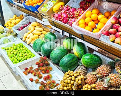 Les vendeurs mettent en place divers fruits exposés dans des paniers sur un marché pendant la journée, attirant les clients à acheter des produits frais. Banque D'Images