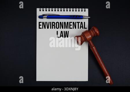 Texte de loi environnementale écrit sur bloc-notes avec marteau sur fond noir Banque D'Images