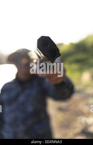 Vue floue d'un joueur déterminé tenant un marqueur de paintball et visant vers l'avant. focus on gun crée une perspective à la première personne pour ce loisir en plein air Banque D'Images