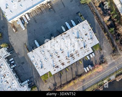 Vue aérienne d'un bâtiment avec des camions garés à proximité, entouré d'asphalte et de verdure, Kent, Washington, États-Unis. Banque D'Images