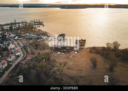 Vue étendue avec un lac, maisons traditionnelles sur pilotis et lumière chaude du coucher de soleil, maisons sur pilotis Unteruhldingen, Bodenseekreis, Allemagne Banque D'Images