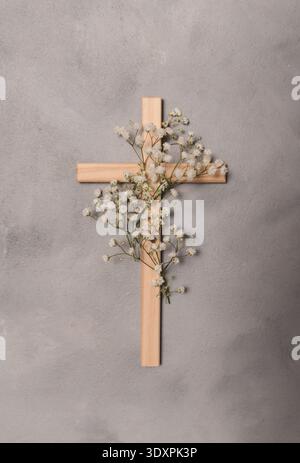 Croix chrétienne en bois décorée de fleurs blanches fraîches de gypsophila. Un symbole religieux de foi, de résurrection et de copyspace du souvenir pour pâques Banque D'Images