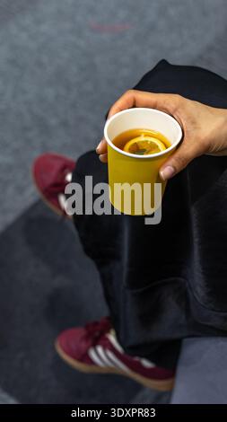 Main tenant une tasse de papier jaune avec thé au citron chaud Banque D'Images