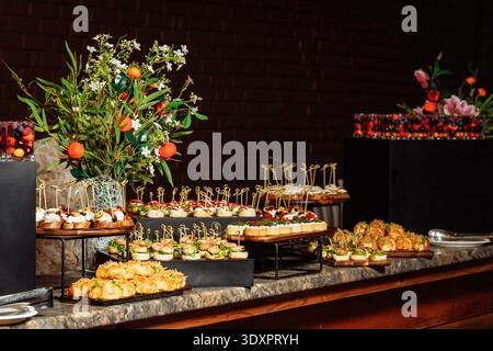 Buffet élégant avec une pièce maîtresse florale sur un comptoir en bois rustique contre un mur de briques Banque D'Images