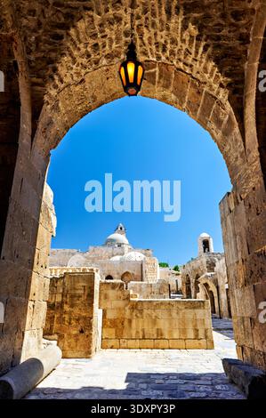 La vue à travers une arche à la Citadelle d'Alep. Le ciel bleu et les structures en pierre sont visibles. Banque D'Images