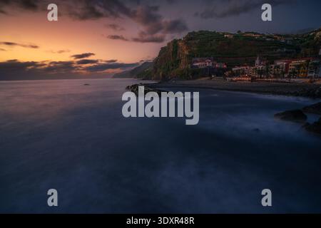 Magnifique coucher de soleil sur la ville côtière de Ponta do sol sur l'île de Madère, Portugal. Les vagues spectaculaires de l'océan Atlantique rencontrent la côte accidentée. Banque D'Images