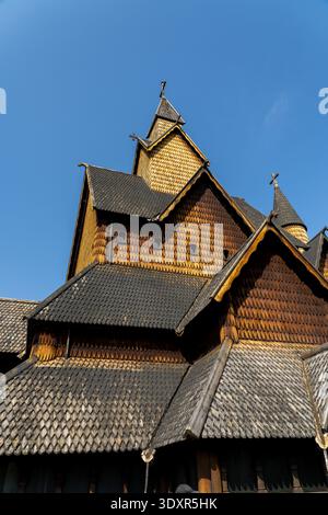Vue sur une majestueuse église en lamelle de bois de Heddal qui s'élève contre un ciel bleu clair, ses sculptures complexes et ses tuiles sombres créant un contraste saisissant, Banque D'Images