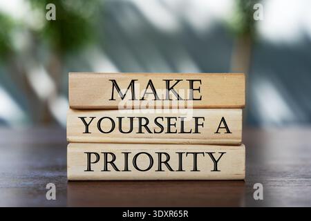 Blocs de bois empilés avec la phrase « FAITES-VOUS Une PRIORITÉ » sur une table en bois. Concept d'autosoins, de santé mentale et de bien-être personnel. Banque D'Images