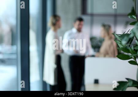 Trois personnes se tiennent devant une fenêtre et se parlent Banque D'Images