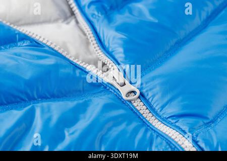 Fermeture éclair gris clair ouverte sur la veste bleue en duvet d'hiver en gros plan. Détail des vêtements Banque D'Images