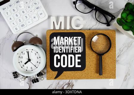 MIC - Market identifier Code acronyme avec calculatrice, réveil et loupe, fond de concept d'entreprise Banque D'Images