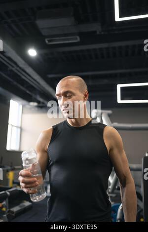 Homme athlétique buvant de l'eau après l'entraînement de gymnastique Banque D'Images